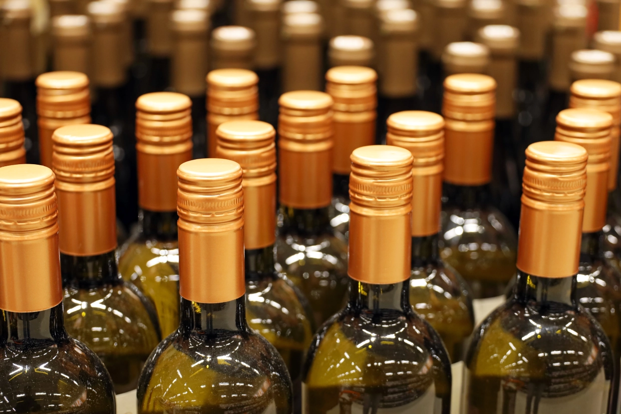 Rows of wine bottles with gold caps.