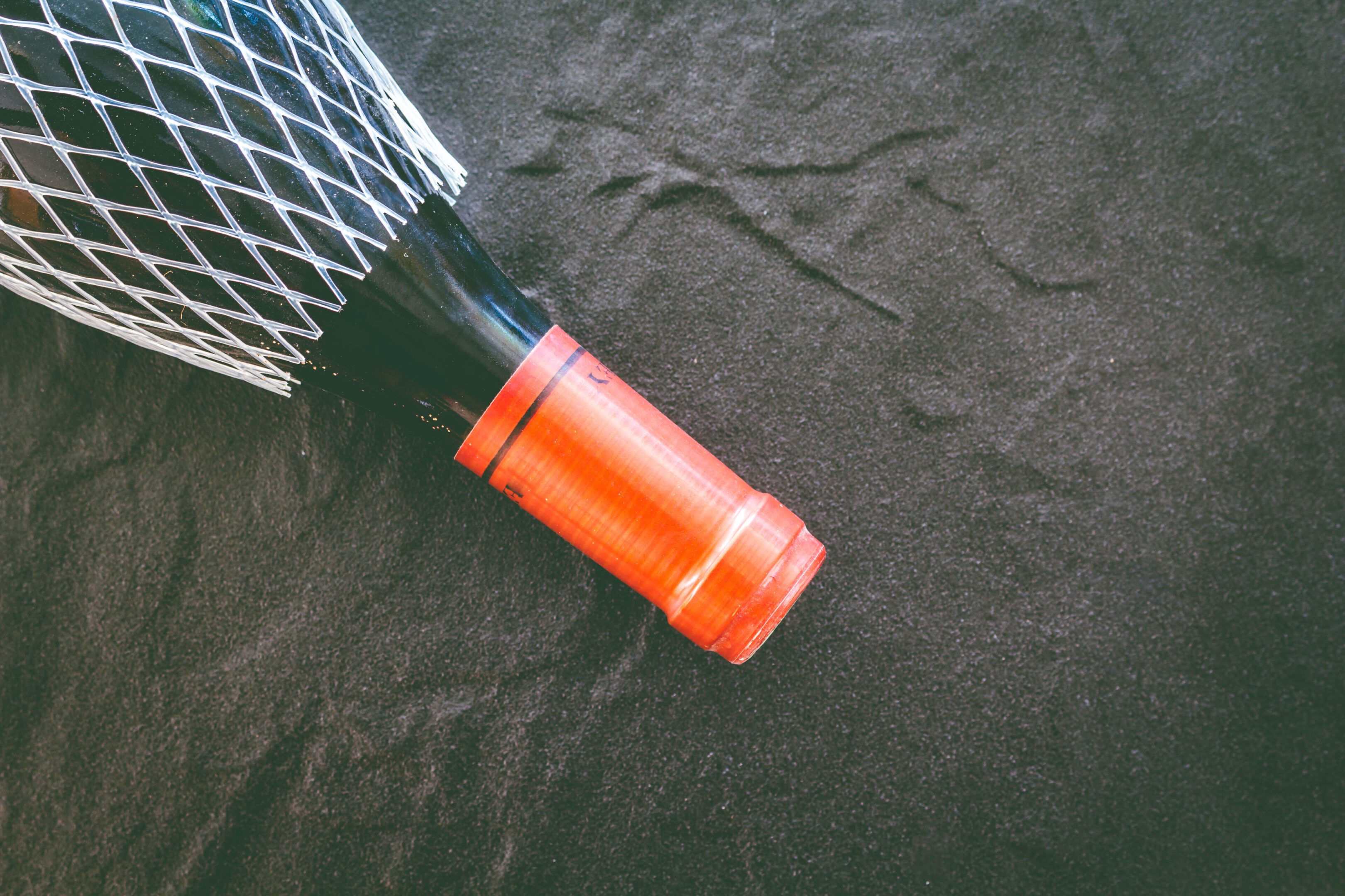 Wine bottle with protective net on fabric.
