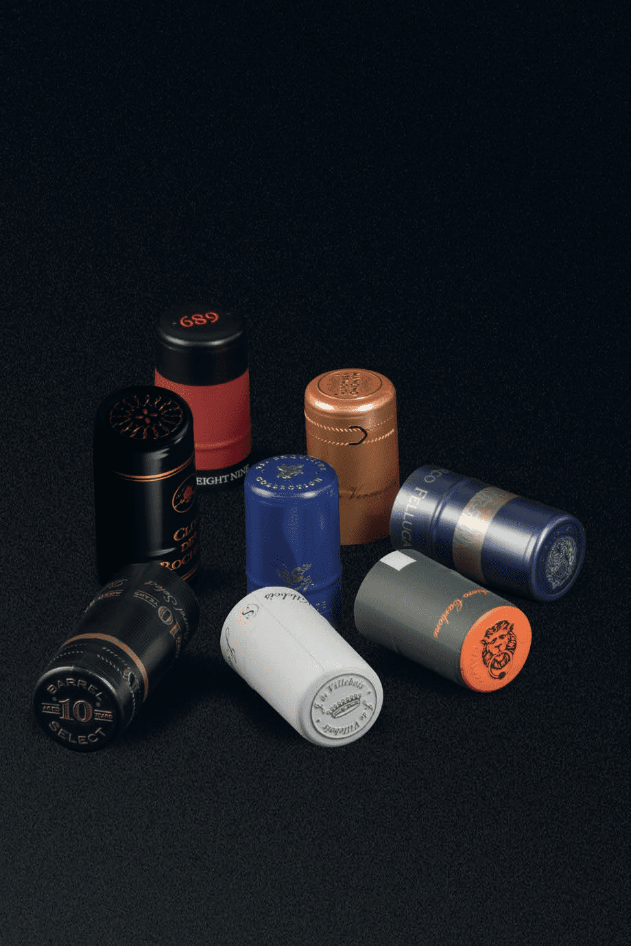 A collection of variously colored and shaped bottle caps on a black surface.